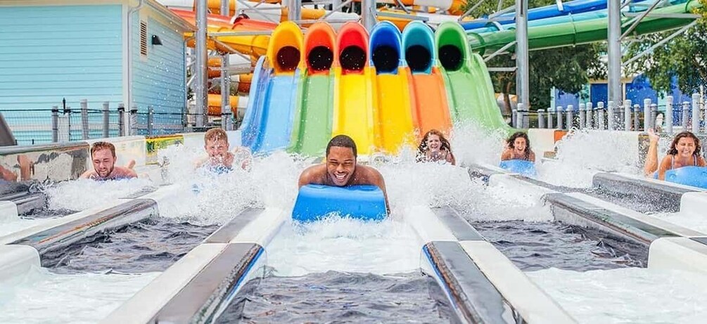 A water park with a multi-colored water slide and people riding water tubes. 1
