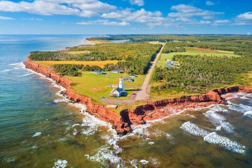 A coastal landscape with a lighthouse, a narrow road, and a forested area. 1