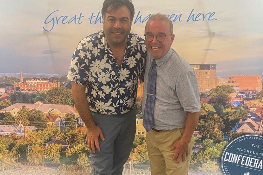 Two men standing in front of a backdrop with a cityscape and the text 'Great things happen here.' 2
