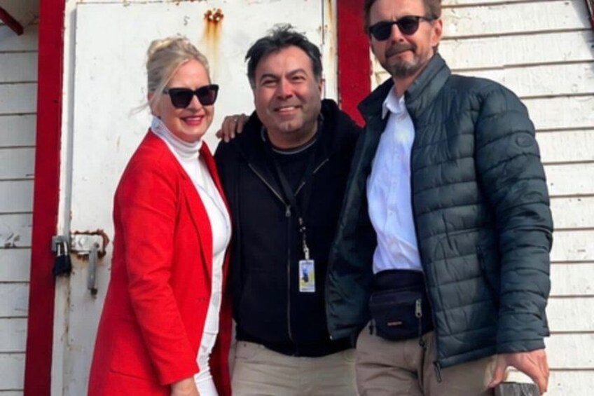 Three people standing in front of a white building with red trim. 4