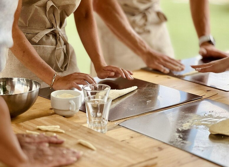 People preparing food, with ingredients and utensils on a wooden table. 1