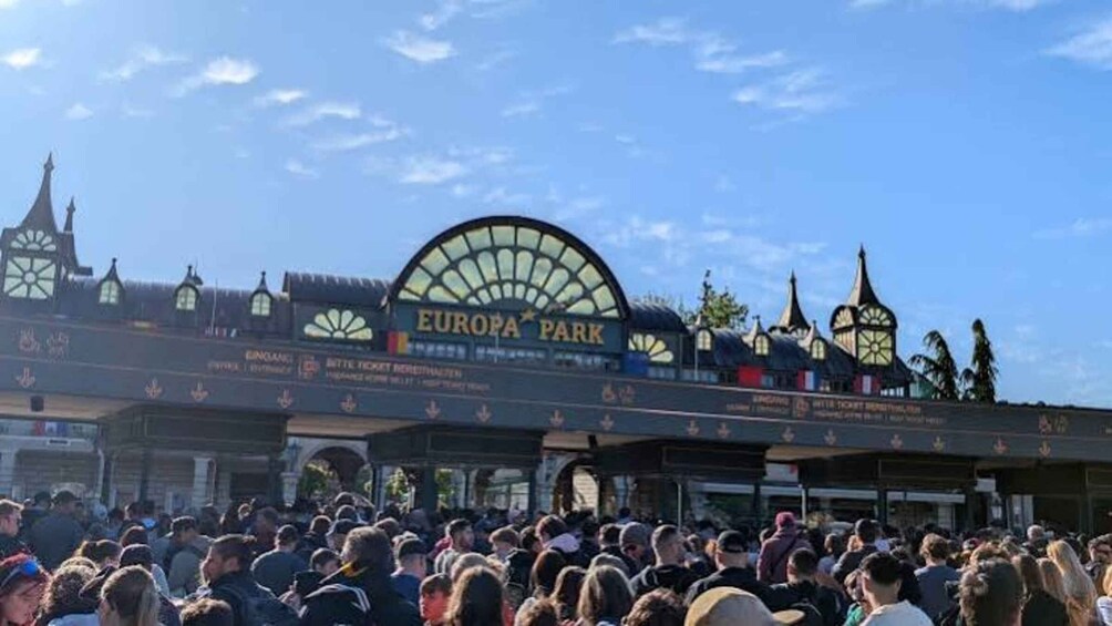 A crowded entrance to Europa Park with a distinctive archway and traditional European architecture. 5