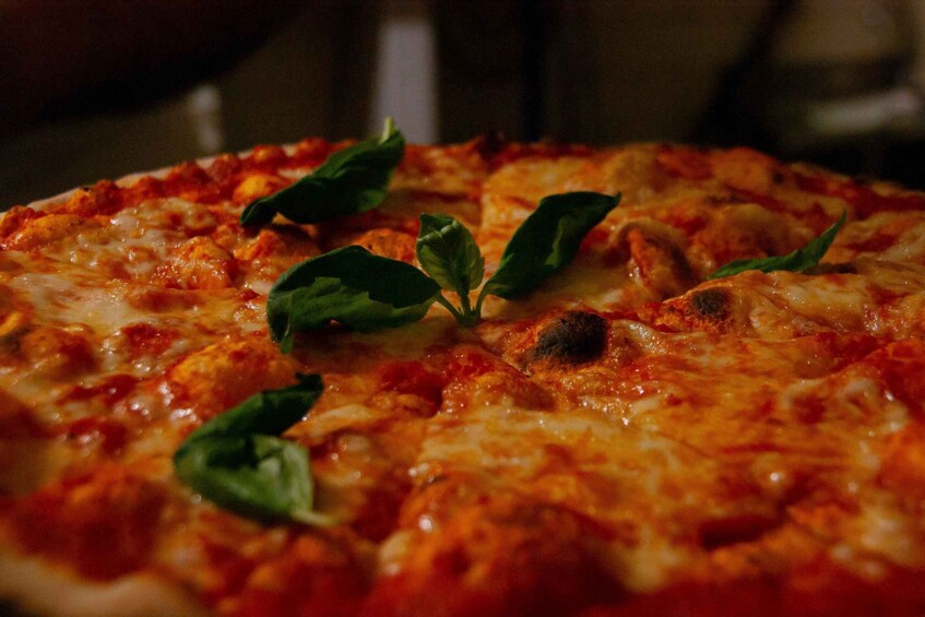 A pizza with melted cheese and basil leaves on top. 5