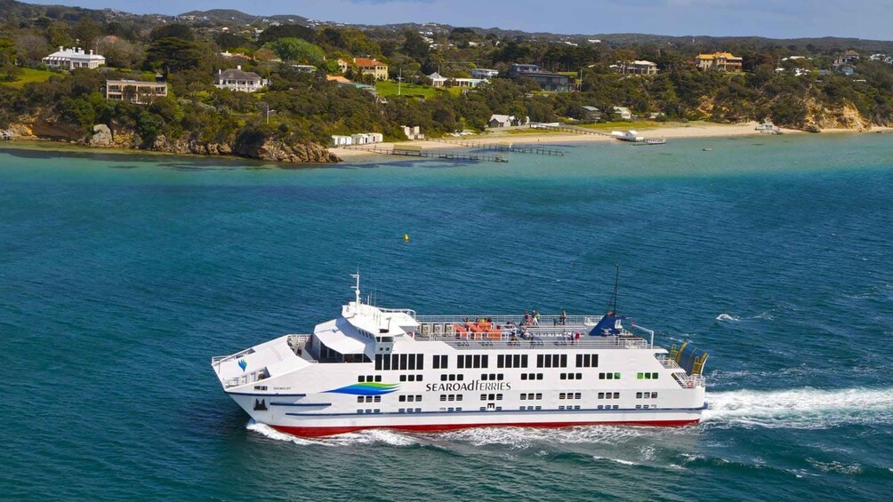 A ferry named 'SEAROADFERRIES' traveling on a body of water with a coastal landscape in the background. 1