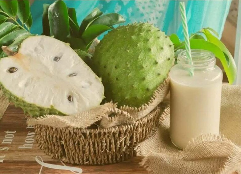 A basket with a sliced fruit, a whole fruit, and a glass of milk on a wooden surface. 4