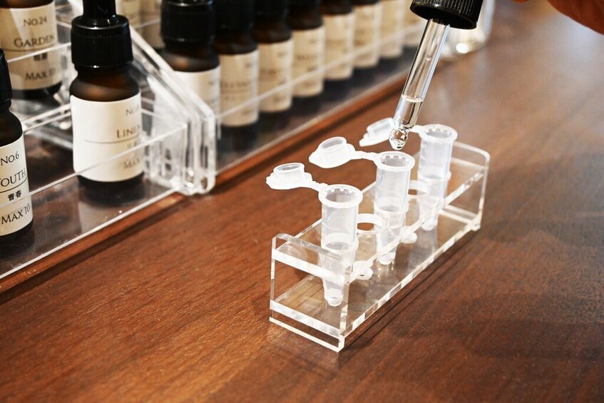 A laboratory setting with a pipette dispensing liquid into test tubes on a rack. 1