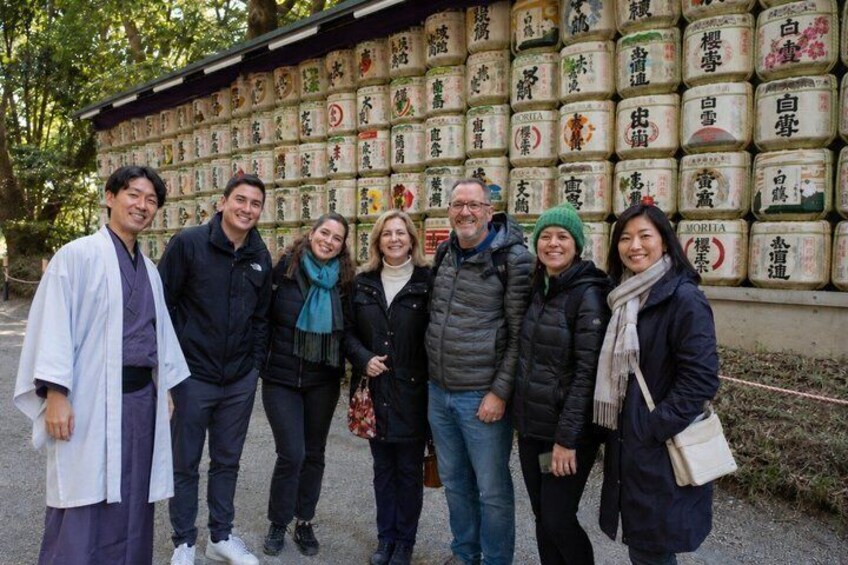 A group of people standing in front of a wall of labeled jars. 1