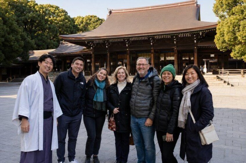 A group of people standing in front of a traditional building with a tiled roof and wooden pillars. 5