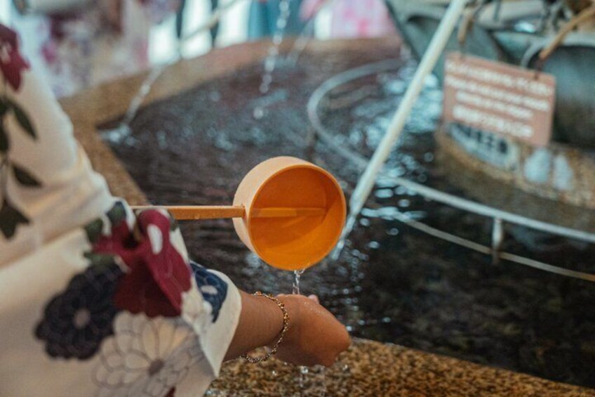 A person pouring a liquid from a yellow cup into a water feature. 3