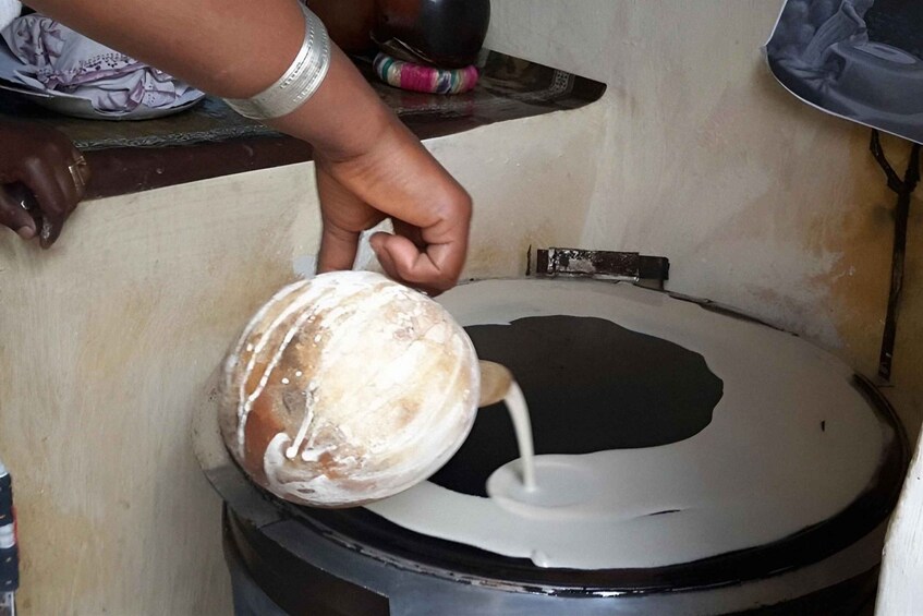 A person pouring a white liquid from a bowl into a black container. 2