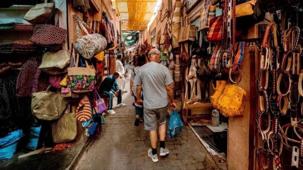 A narrow market street with various bags and textiles on display. 3
