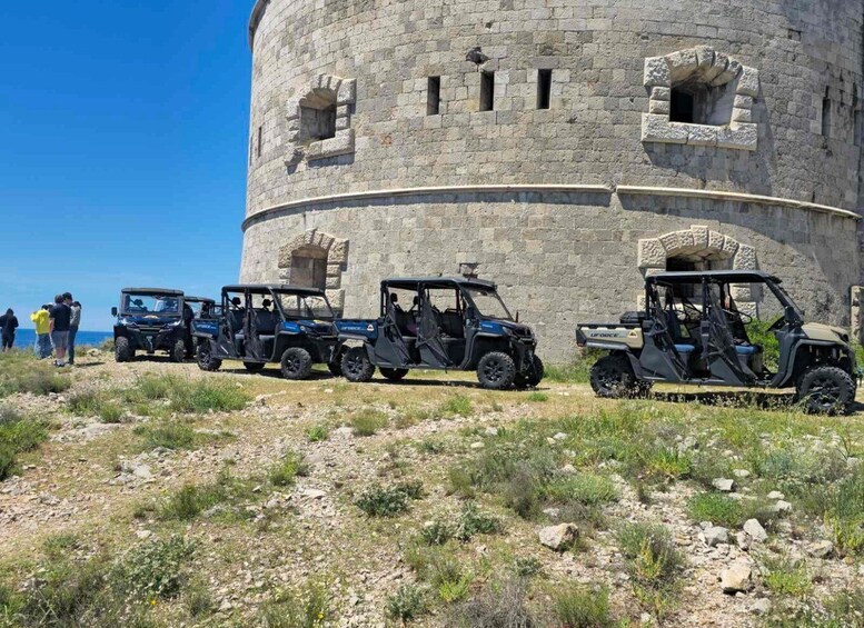 A group of off-road vehicles parked in front of a stone tower. 5