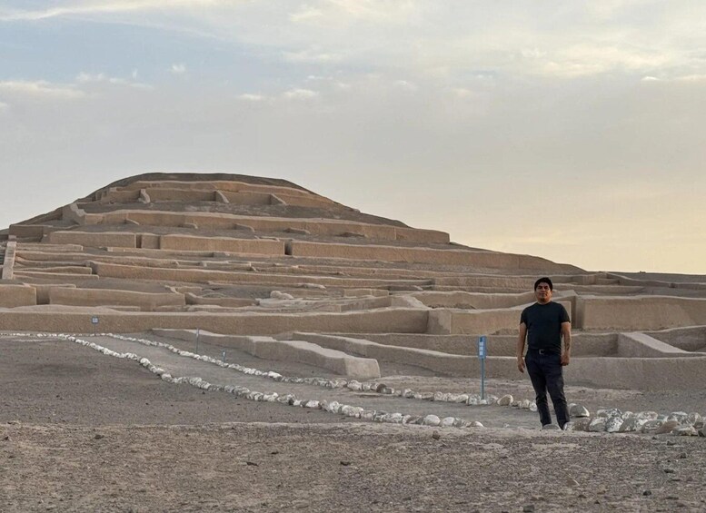 A person standing in front of a large, stepped pyramid structure. 2
