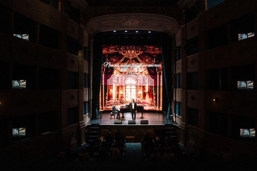 An ornate theater interior with a stage, seating, and a chandelier. 3