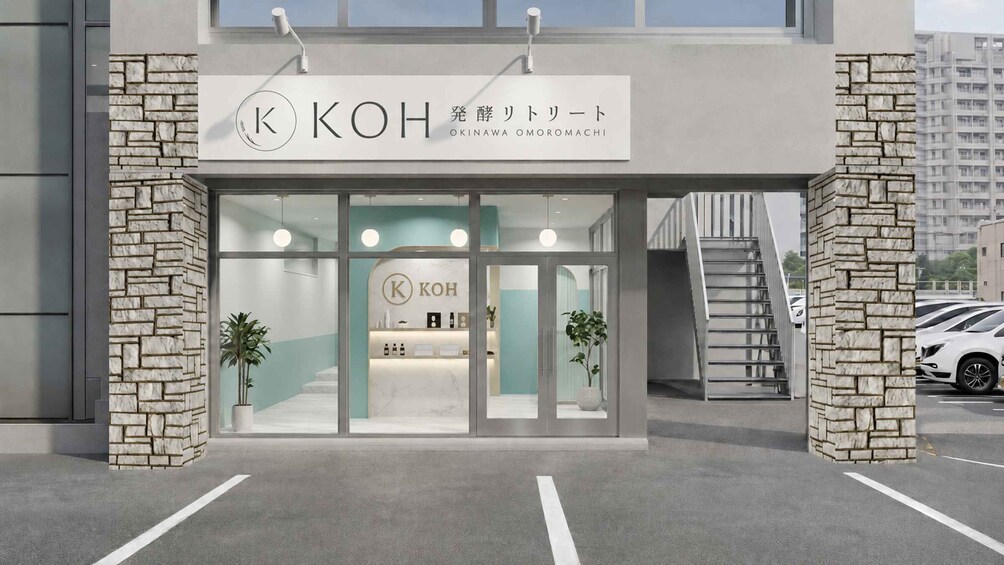 A modern building with a stone facade, a sign reading 'OKINAWA OMOROMACHI,' and a staircase leading to the entrance. 5