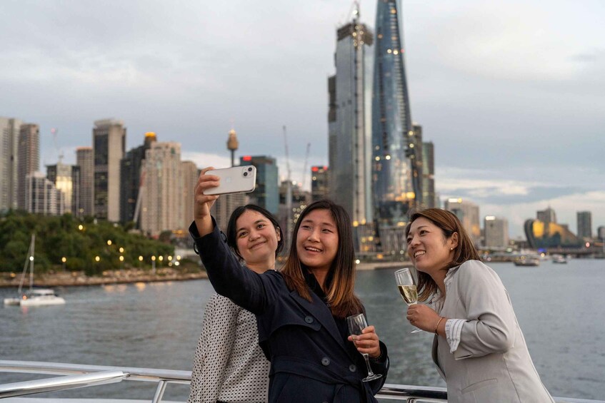 Three people taking a selfie on a boat with a city skyline in the background. 3