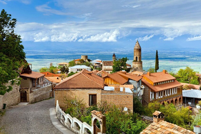 A coastal town with historic buildings, a prominent church tower, and a clear view of the sea. 1