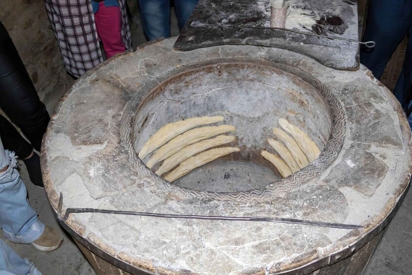 A traditional stone oven with dough sticks inside. 5