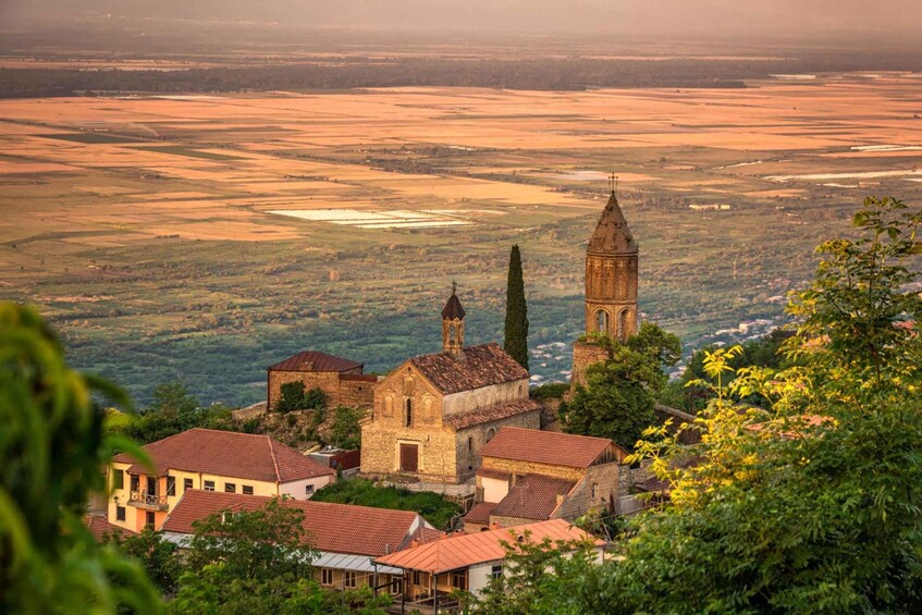 A historic town with a prominent church and tower, surrounded by lush greenery and a vast landscape. 3