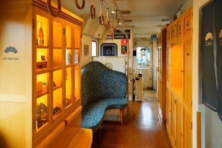 A narrow corridor with a patterned bench, wooden cabinets with glass doors, and a sign for a cafe. 5