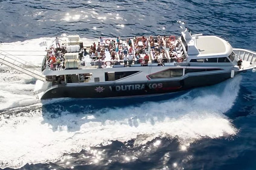 A boat named 'OUTIRA COS' with passengers on deck, moving through the water. 3