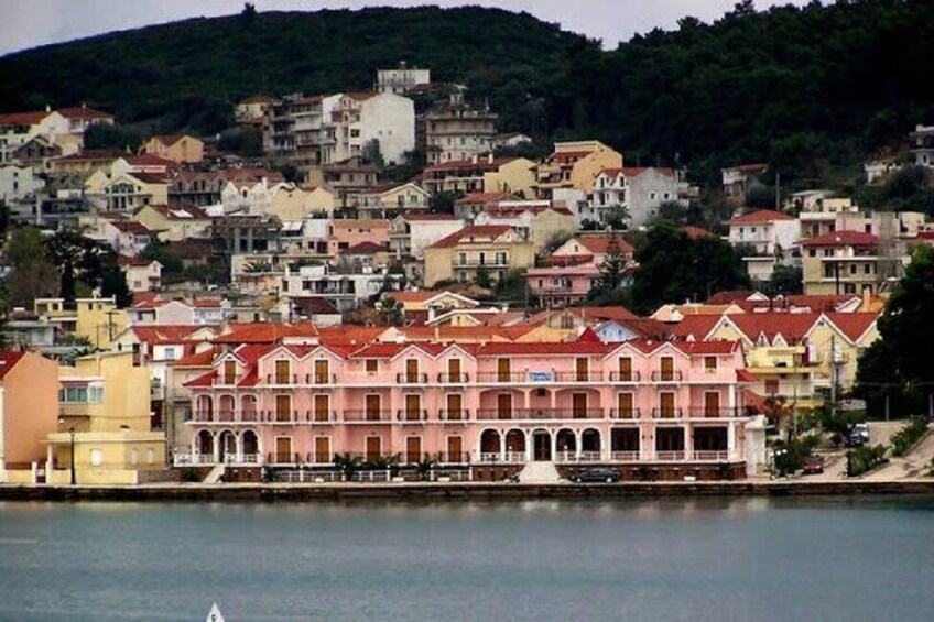 A coastal town with colorful buildings, a waterfront, and a hill in the background. 1