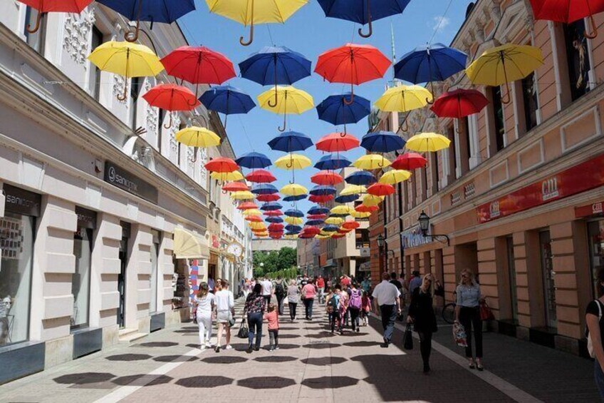 A street with colorful umbrellas suspended above, lined with shops and pedestrians. 4
