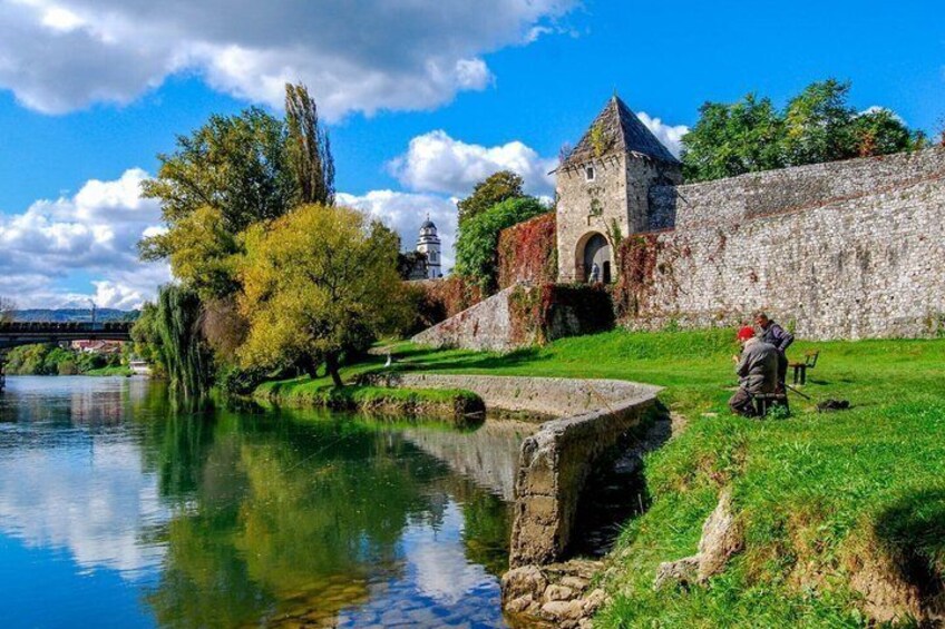 A historic stone wall, a river, and a small bridge. 5