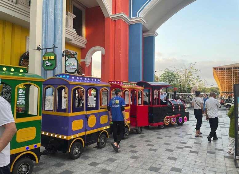 A colorful train ride with passengers and a store nearby. 3