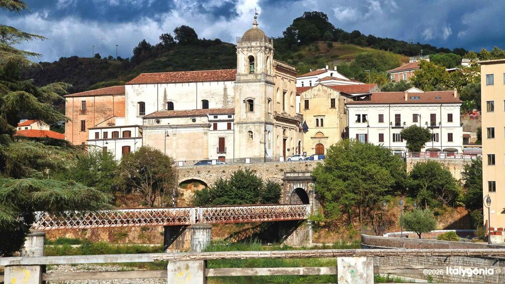 A historic church with a bell tower, a bridge, and surrounding residential buildings. 1