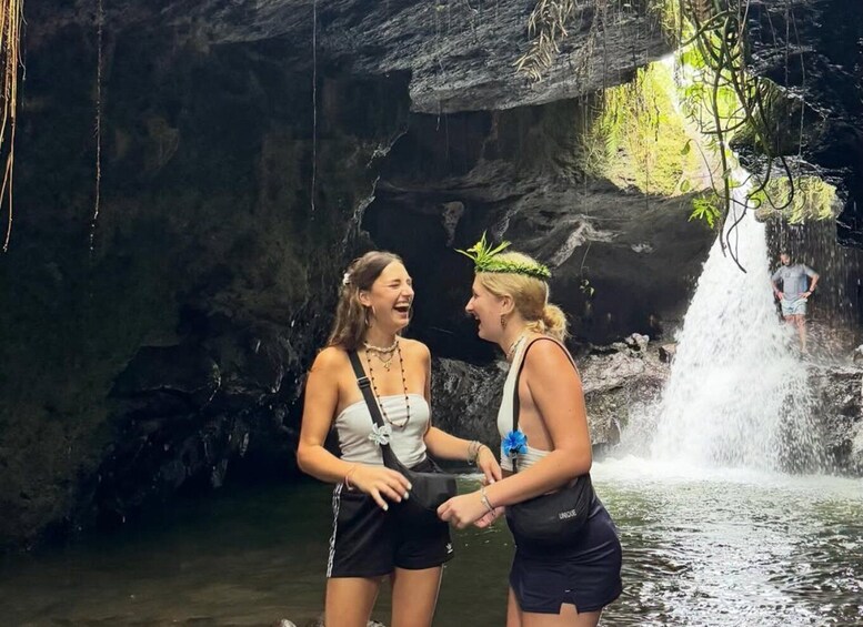 Two people standing by a waterfall in a rocky cave. 4