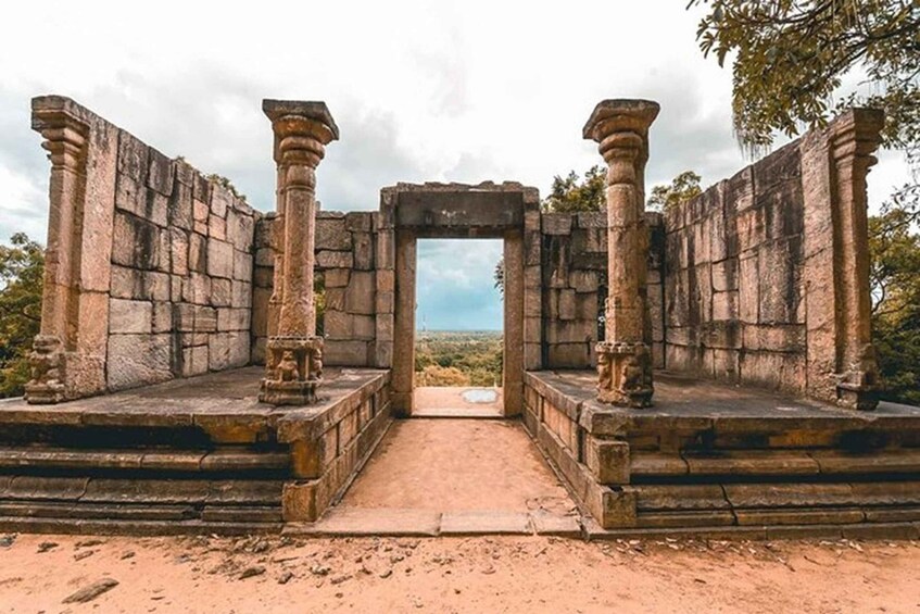 Ancient stone ruins with a central doorway framed by columns. 1