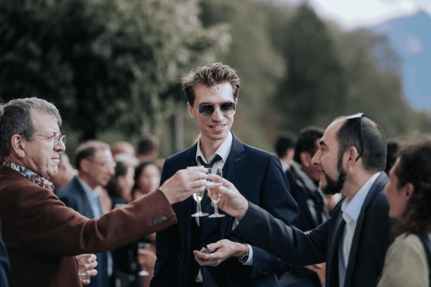 A group of people toasting with wine glasses in an outdoor setting. 5