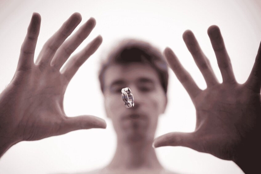 A person holding a small object between their hands. 1