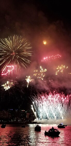 Fireworks over a body of water with boats. 5