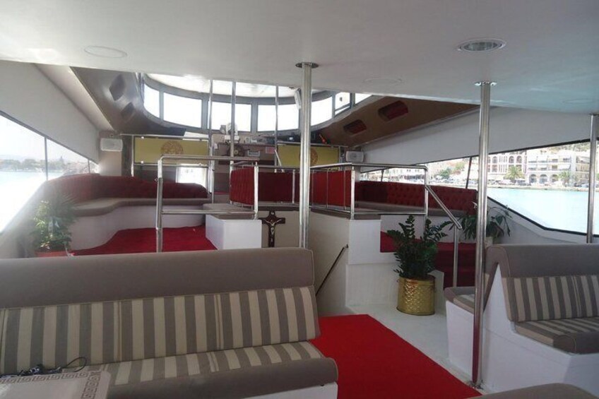 A boat interior with a red carpet, striped sofa, and a potted plant. 4