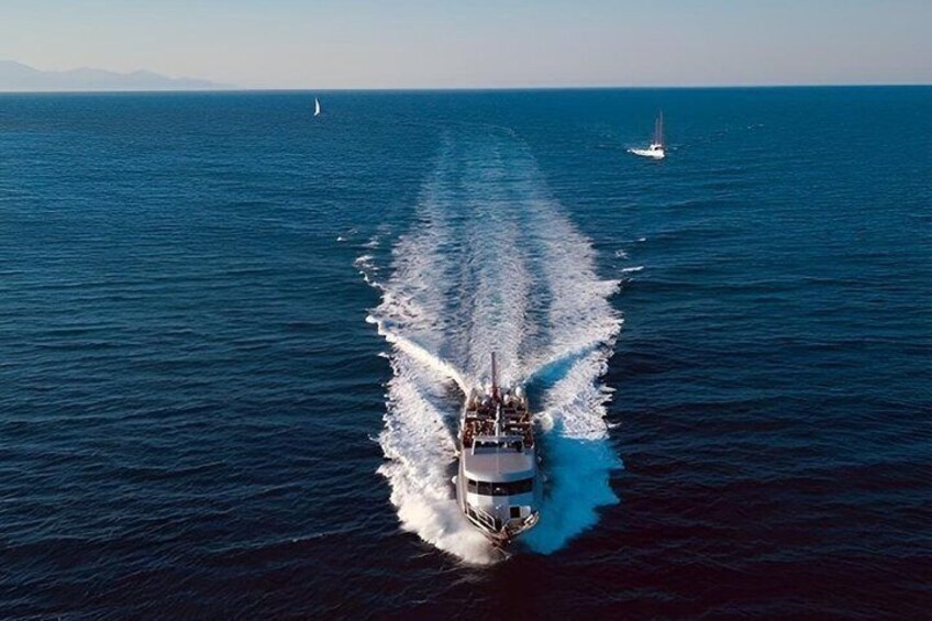 A ship creating a wake in the ocean with a sailboat in the distance. 1
