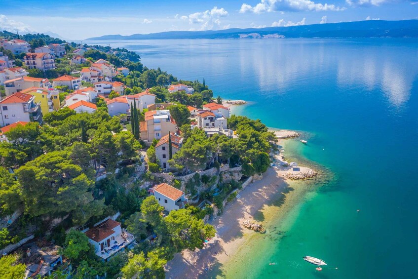 A coastal village with buildings, a beach, and clear blue waters. 2