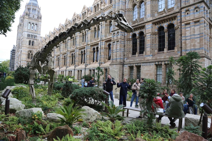 A dinosaur skeleton in a garden with people around it. 3