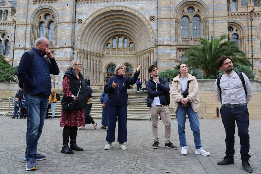 A group of people standing in front of a large, ornate building with arched windows and a central dome. 5
