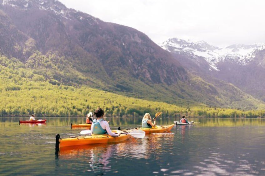 People kayaking on a calm lake surrounded by mountains. 5
