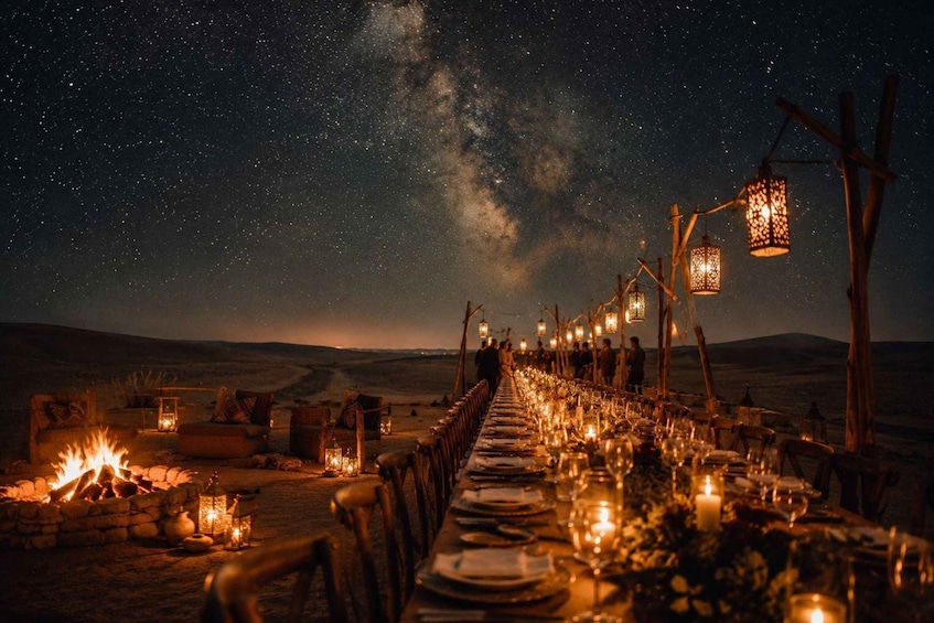 A desert dinner setup with a long table under starry skies. 3