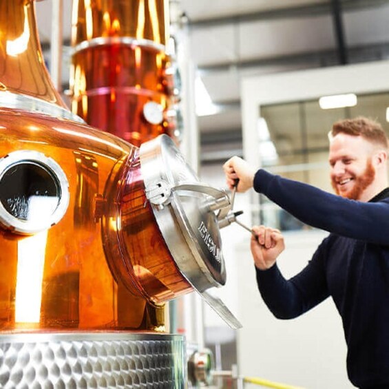 A person working on a large copper distillation apparatus. 1