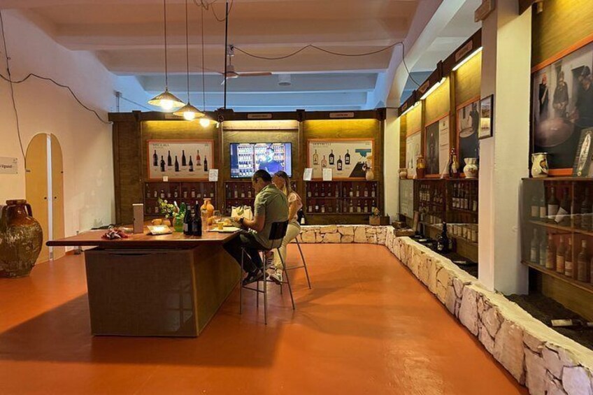 A bar with a stone counter, shelves with bottles, and a TV screen. 2