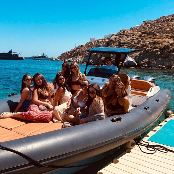 A group of people on a small inflatable boat near a rocky coastline with clear blue water. 2