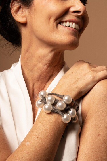 A person wearing a white garment with a pearl necklace. 3