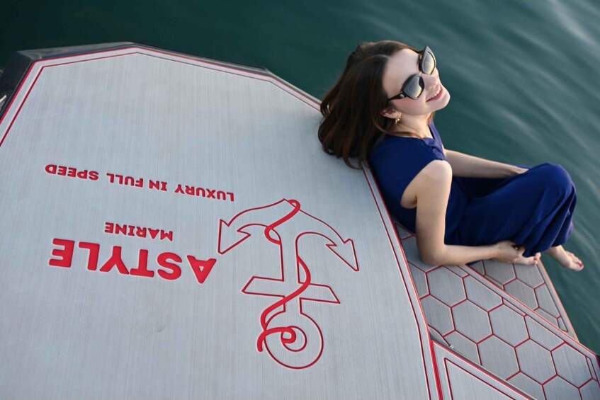 A person sitting on a surfboard with 'MARINE ASTYLE' and 'LUXURY IN FULL SPEED' written on it. 3