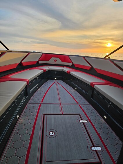 A boat interior with red and white seating, a central control panel, and a sunset view. 2