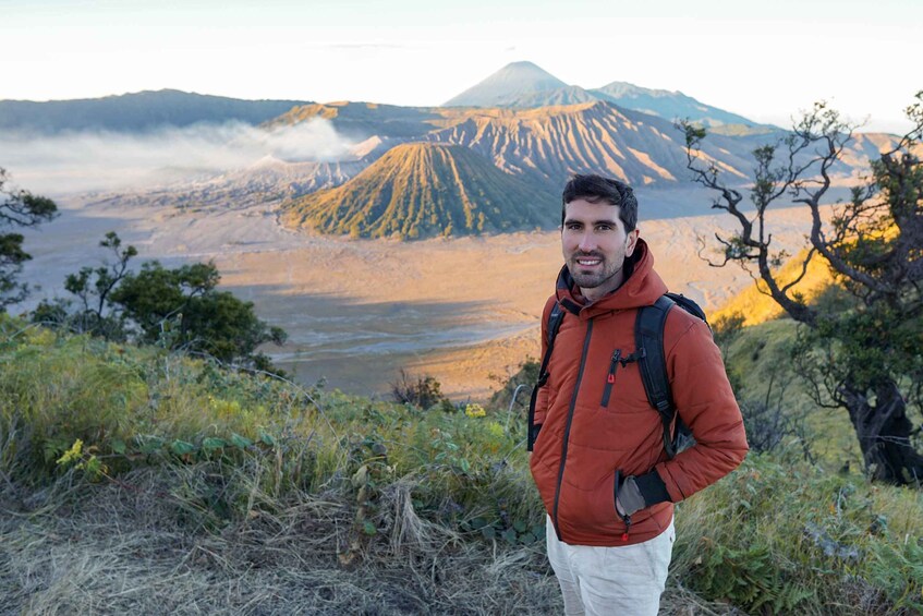 A person standing on a hill with a mountainous landscape in the background. 3