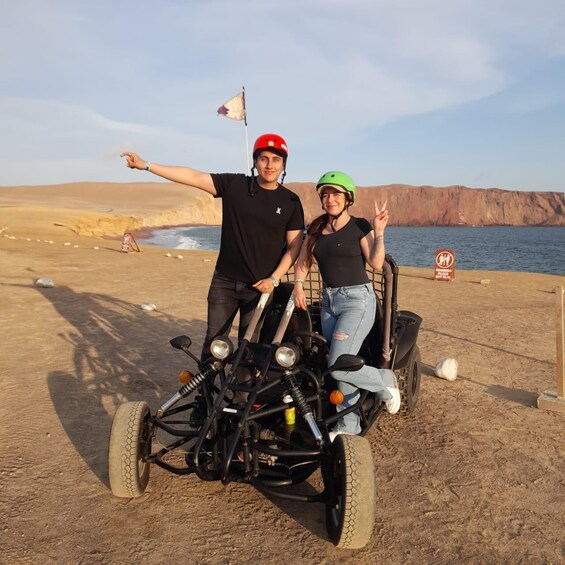 To personer i en sandbuggy med et ørkenlandskab og et vandareal i baggrunden. 4